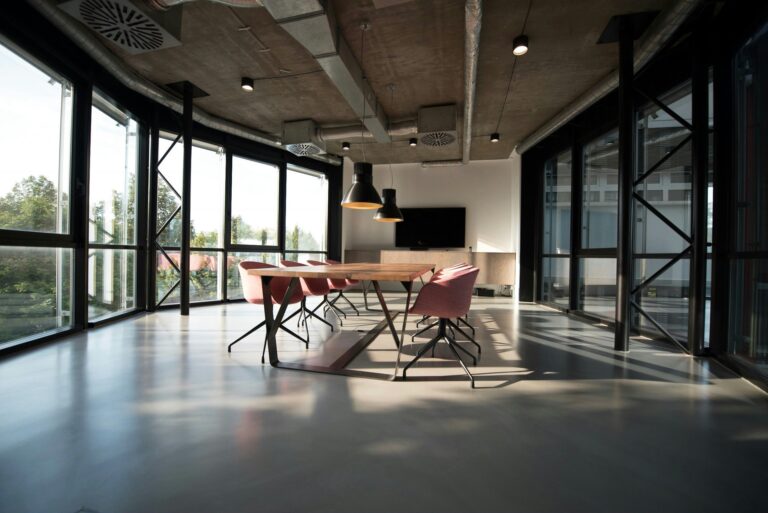 Büro mit großer Fensterfront und sichtbarem Lüftungssystem an der Decke